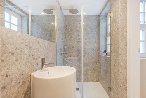 ein weißes Bad mit einem Waschbecken und einer Dusche in der Unterkunft As Vizinhas Boutique Apartments in Porto
