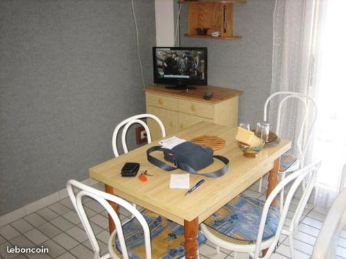 - une table en bois avec des chaises et un sac dans l'établissement Les indes galantes, au Cap d'Agde