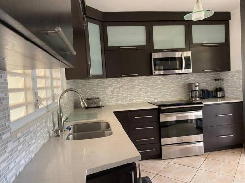 a kitchen with a sink and a microwave at Villa Del Carmen Family Vacation Home in Isabela