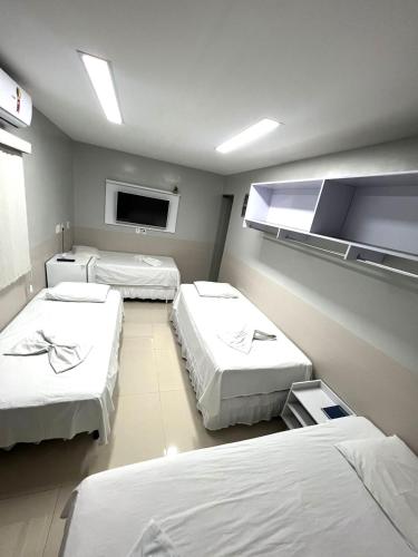 a hospital room with three beds and a tv at TERESINA HOTEL in Teresina