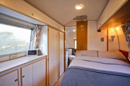 Habitación pequeña con cama y ventana en The Airstream, en Penryn