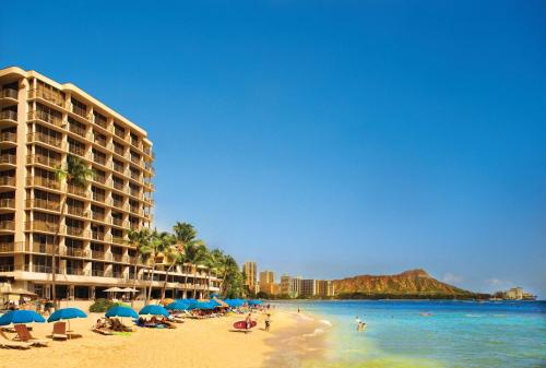 una spiaggia con ombrelloni e persone sulla sabbia di OUTRIGGER Reef Waikiki Beach Resort a Honolulu