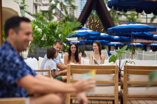 a group of people sitting at tables in a restaurant at Outrigger Reef Waikiki Beach Resort in Honolulu