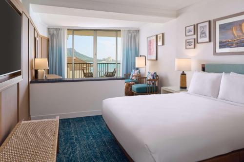 ホノルルにあるOUTRIGGER Reef Waikiki Beach Resortのベッドと大きな窓が備わるホテルルームです。
