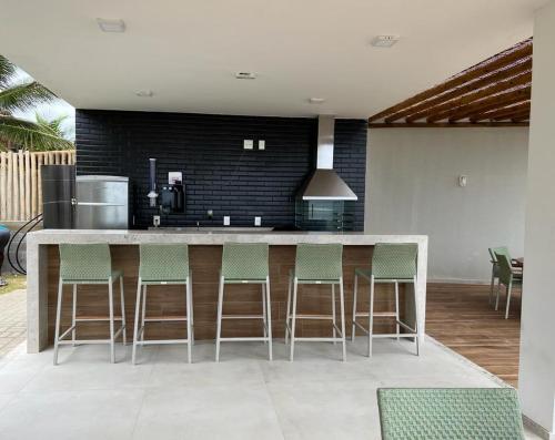 a kitchen with a bar with green bar stools at Casa Califórnia in Itacimirim