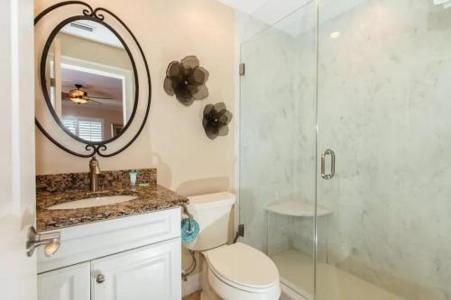 a bathroom with a shower and a toilet and a mirror at SANDPIPER BEACH 205 in Sanibel