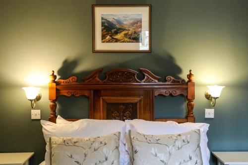 a bed with a wooden headboard and a picture on the wall at The Black Swan in Ravenstonedale