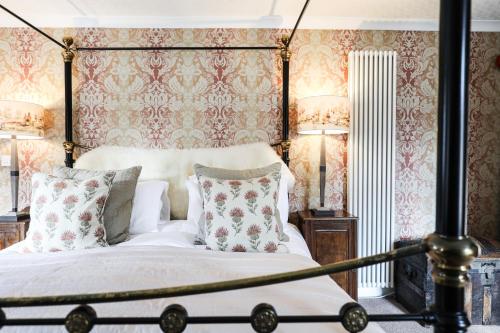 a bedroom with a canopy bed with floral wallpaper at The Black Swan in Ravenstonedale