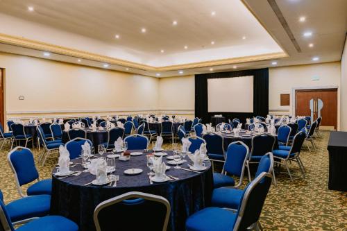 a conference room with tables and chairs and a screen at Holiday Inn Merida by IHG in Mérida