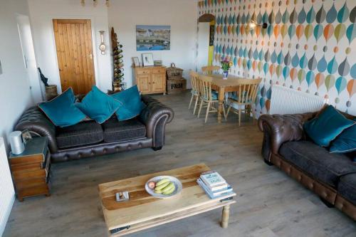 a living room with leather couches and a table at Luxury, Modern Barn Conversion in Thursford