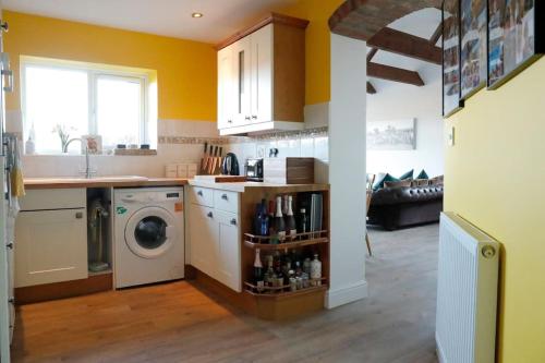 a kitchen with a washing machine and a washer at Luxury, Modern Barn Conversion in Thursford