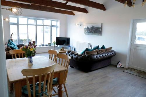 a living room with a table and a couch at Luxury, Modern Barn Conversion in Thursford
