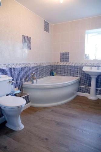a bathroom with a tub and a toilet and a sink at Luxury, Modern Barn Conversion in Thursford