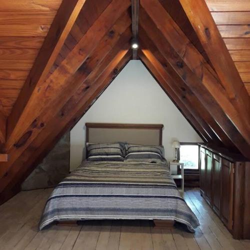 a bedroom with a bed in an attic with wooden ceilings at Cabaña La pionera in San Carlos de Bariloche