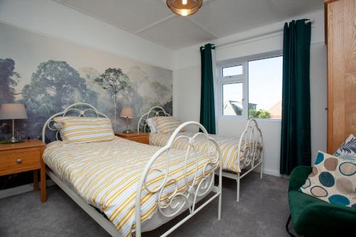 a bedroom with three beds and a window at Seymour House in Exmouth