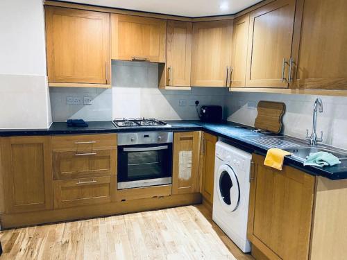 cocina con armarios de madera, lavadora y secadora en One bedroom apartment near Dalston Station en Londres