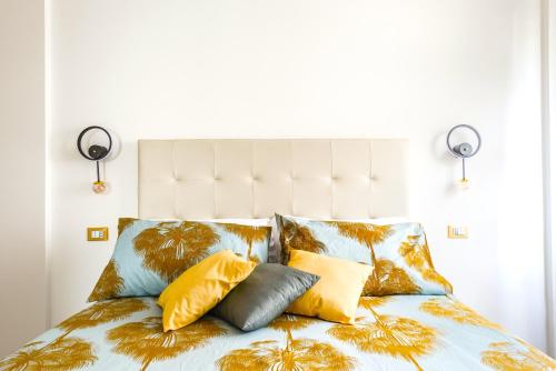 a bed with yellow and blue pillows on it at Hostly - Cisanello Suite Apartment - Light and Colors in Pisa