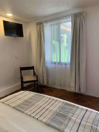 a bedroom with a bed and a chair and a window at Hotel La Cofradía in Zacatlán