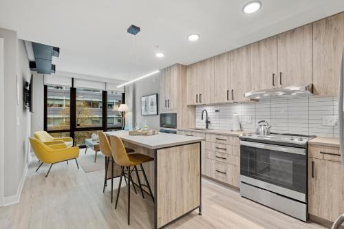a kitchen with wooden cabinets and yellow chairs at Coda on Half, a Placemakr Experience - Navy Yard in Washington