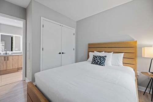 a white bedroom with a large bed and a bathroom at Coda on Half, a Placemakr Experience - Navy Yard in Washington