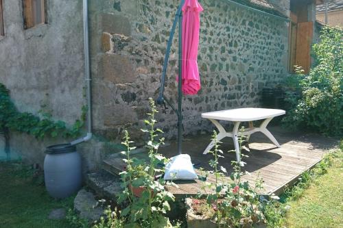 a pink umbrella and a table in a garden at Chez Philopin in Saint-Pierre-Colamine