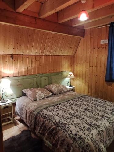 une chambre avec un lit dans une pièce aux murs en bois dans l'établissement Chez Philopin, à Saint-Pierre-Colamine