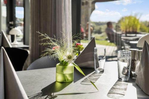 a table with a green vase with flowers on it at Best Western Plus Hotel Fredericia in Fredericia
