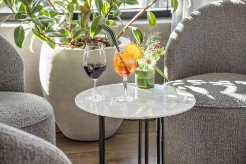 two glasses of wine on a table next to two chairs at Best Western Plus Hotel Fredericia in Fredericia
