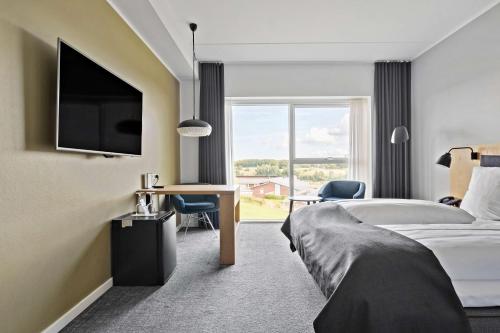 a hotel room with a bed and a desk and a television at Best Western Plus Hotel Fredericia in Fredericia