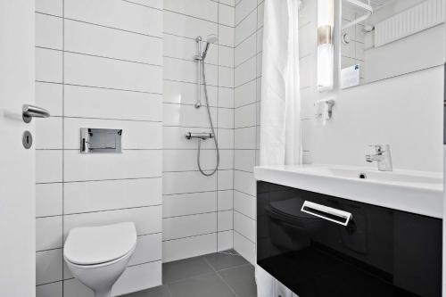 a white bathroom with a toilet and a sink at Best Western Plus Hotel Fredericia in Fredericia