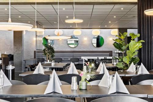 a restaurant with tables and chairs with white napkins at Best Western Plus Hotel Fredericia in Fredericia