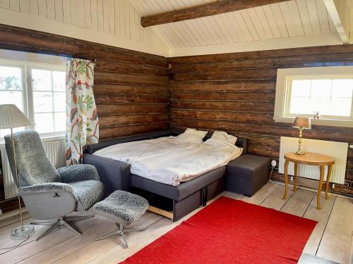 um quarto com uma cama, uma cadeira e um tapete vermelho em Backgårdens Timmerstuga em Falköping
