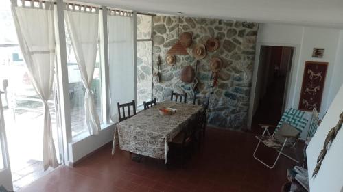 comedor con mesa y pared de piedra en La casita de Calamuchita en Los Reartes