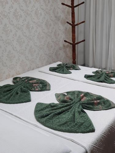 a group of three beds with green towels on them at Mini Casa independente no bairro Praia das Gaivotas in Vila Velha
