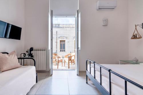 a white bedroom with a bed and a balcony at Merabulò in Lecce