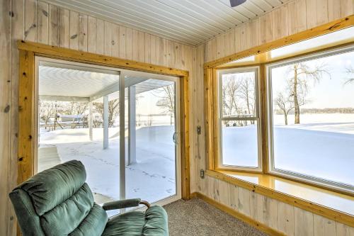 a living room with a green chair and windows at Stunning Waterville Home on Tetonka Lake! in Waterville
