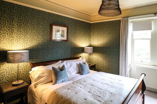 a bedroom with a large bed with green wallpaper at The Black Swan in Ravenstonedale