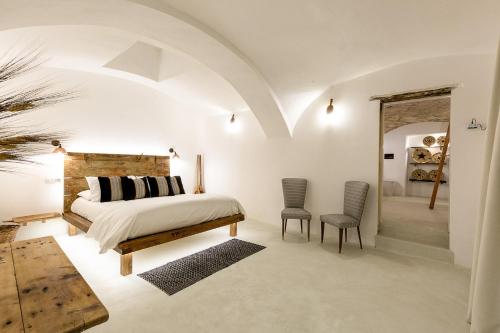 a bedroom with a bed and two chairs at Crobi Museum and Suites in Cagliari