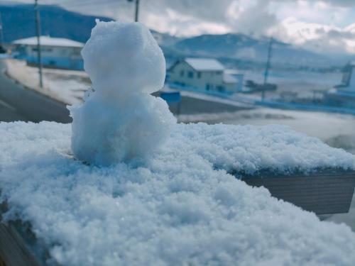 a small snowman sitting on top of a pile of snow at Family Hotel Matsumoto Satoyama Doors in Matsumoto