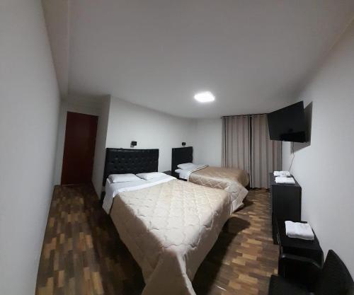 um quarto de hotel com duas camas e uma televisão de ecrã plano em RONALD HOTEL em Churín