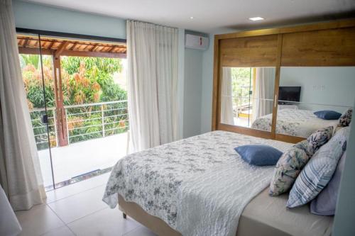 1 dormitorio con cama grande y ventana grande en Casa - Arraial D'ajuda-Ba, en Porto Seguro