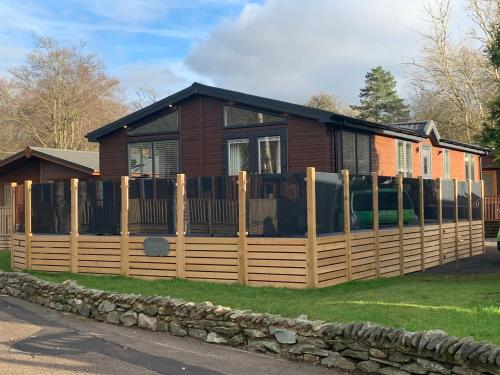 a house with a wooden fence in front of it at Thirlmere 4 Luxury Lodge at White Cross Bay Windermere in Windermere
