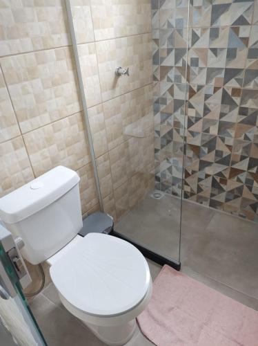 a bathroom with a white toilet and a shower at Espaço Zoey in Búzios