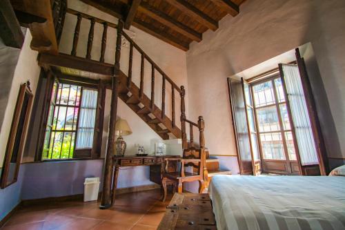 a bedroom with a bed and a desk and windows at Meson del Alferez Xalapa in Xalapa