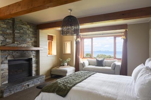a bedroom with a fireplace and a bed and a couch at Hillbrook Estate Whangamata in Opoutere
