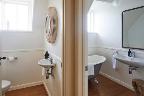 a bathroom with two sinks and a tub and a mirror at Hillbrook Estate Whangamata in Opoutere