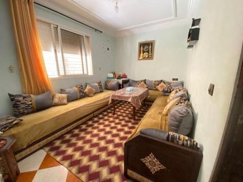 Grande maison Calme في مكناس: غرفة معيشة مع أريكة طويلة وطاولة