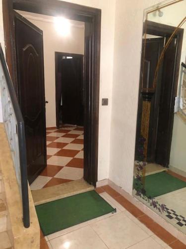 a hallway with two doors and a checkered floor at Grande maison Calme in Meknès