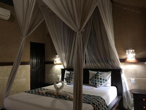 - une chambre avec un lit à baldaquin dans l'établissement Pondok Shindu Guest House, à Pemuteran