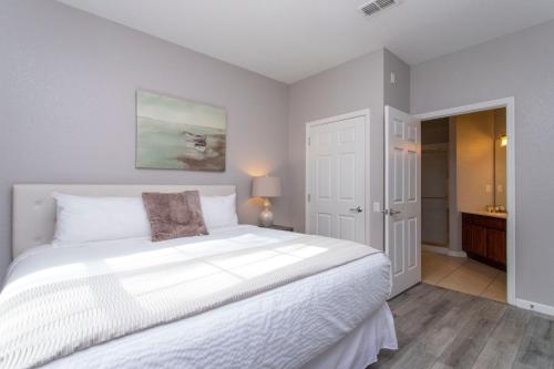 1 dormitorio con 1 cama blanca grande y baño en Magnificent 2 Bedroom Apartment Vista Cay Resort 107, en Orlando